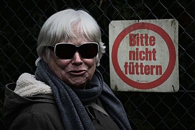Close-up portrait of senior woman wearing warm clothing by chainlink fence