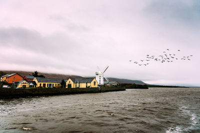 Birds flying over lake against sky