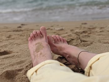 Low section of woman relaxing on sand