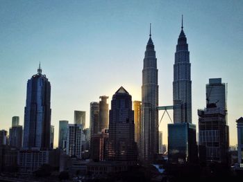 Petronas towers in city against clear sky during sunset