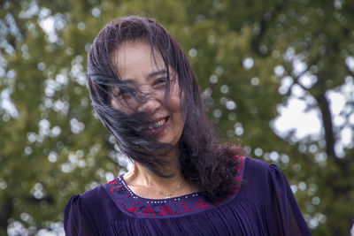 Portrait of smiling senior woman against tree