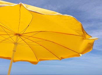 Low angle view of yellow parasol against sky