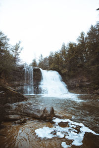 Scenic view of waterfall against sky during winter