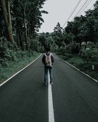 Rear view of people walking on road amidst trees