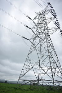 Low angle view of electricity pylon on field against sky