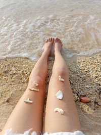 Low section of woman on sand at beach