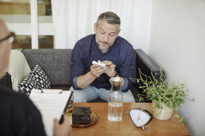 Sad mature man with tissue sharing problems during therapy session