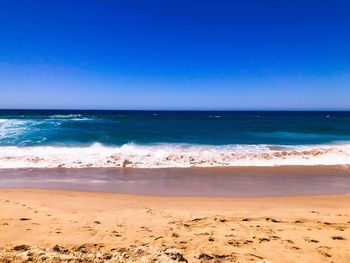 Scenic view of beach against blue sky