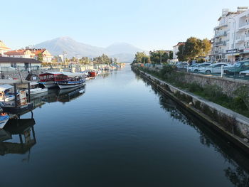 Boats moored in river by city against sky