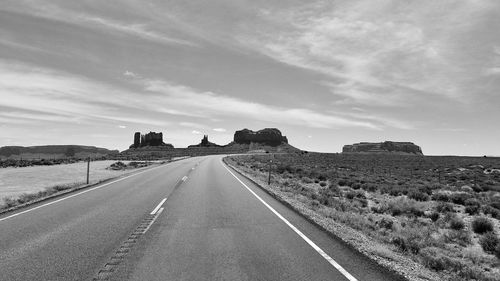 Road leading towards landscape against sky