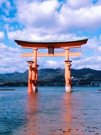 View of cross on sea against cloudy sky