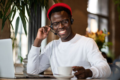 Smiling man wearing headphones sitting at cafe