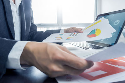 Midsection of businessman analyzing graph table at office