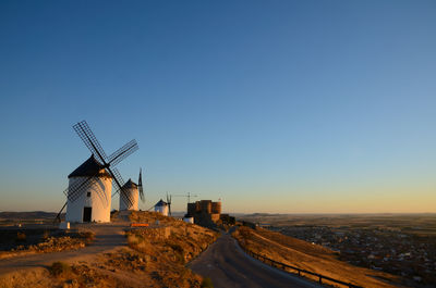 Traditional windmill on landscape against clear blue sky