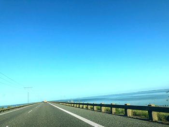 Empty road against clear blue sky
