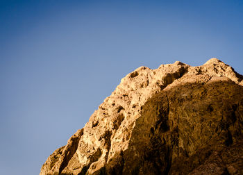 Low angle view of rock formations against clear blue sky