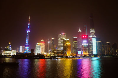 Illuminated city and river against clear sky at night