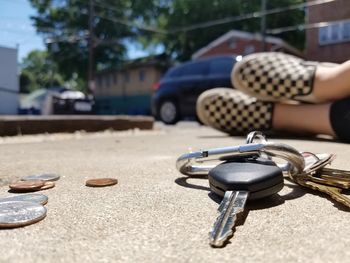 Close-up of coins and key by man on footpath