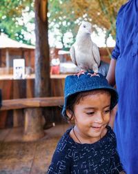 Cute girl with bird on head standing outdoors