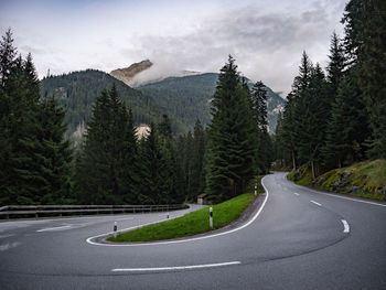 Mountain road amidst trees against sky