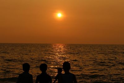 Silhouette people on beach against sky during sunset