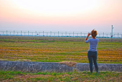 Rear view of man standing by sea against sky during sunset