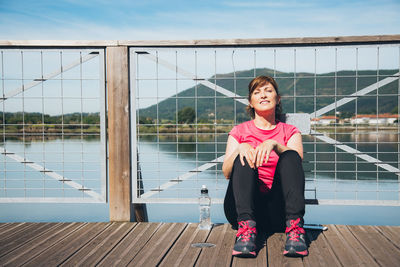 Portrait of woman against railing against sky