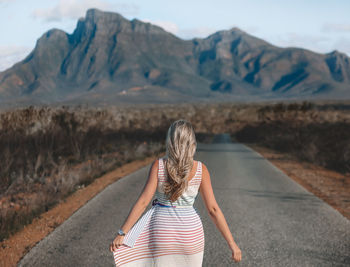 Rear view of woman standing on road against mountain