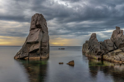 Scenic view of rock formation in sea against sky