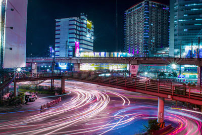 Light trails on road against buildings at night