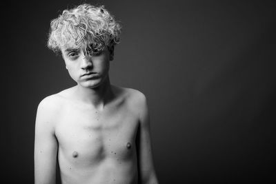 Portrait of shirtless boy against black background