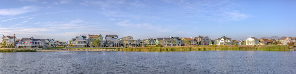 River by houses against buildings in city against sky