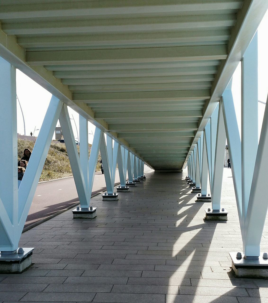 built structure, the way forward, indoors, architecture, ceiling, diminishing perspective, architectural column, column, in a row, empty, long, vanishing point, corridor, sunlight, transportation, connection, support, bridge - man made structure, railing, shadow