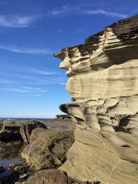 Rock formation on shore against sky