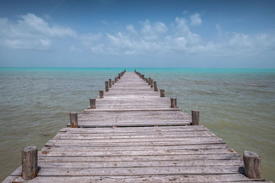 Wooden pier on sea against sky