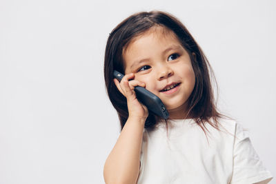 Portrait of young woman talking on phone against white background