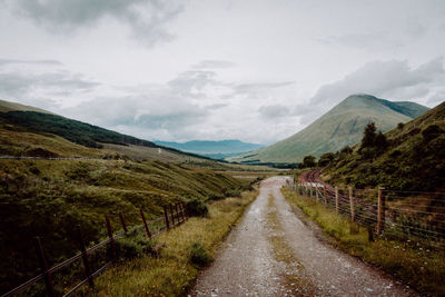 Road leading towards mountains against sky