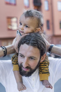 Mid adult man carrying son on shoulders outdoors