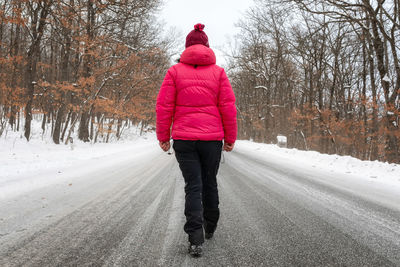 Rear view of man walking on snow covered road