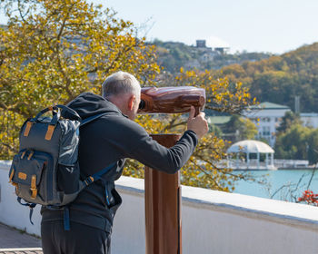 A man looks through a tourist telescope at the lake and mountains. autumn landscape.