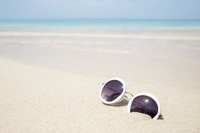 Close-up of sunglasses on beach against sky