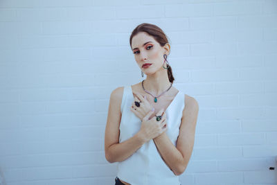 Portrait of a young woman standing against wall