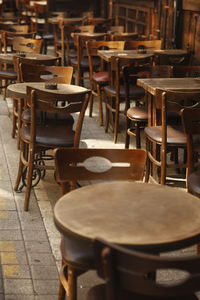 Empty chairs and tables at sidewalk cafe against building