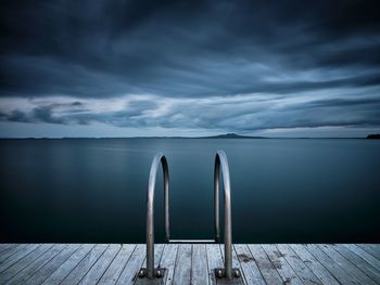 Jetty in sea against cloudy sky