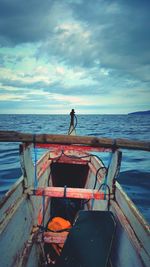 Man standing on boat at sea shore against sky