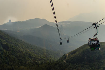 Overhead cable car over mountains against sky