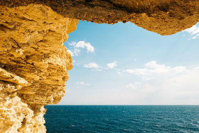 Rock formation by sea against sky