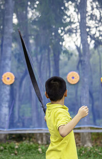 Side view of boy practicing archery in park