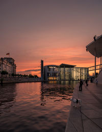 Buildings by sea against sky during sunset