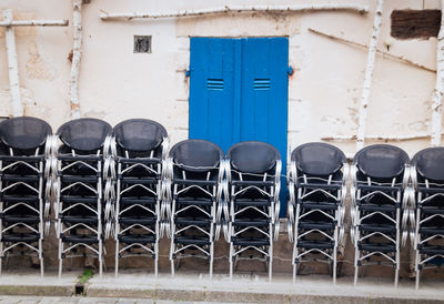 Stack of metallic chairs against building